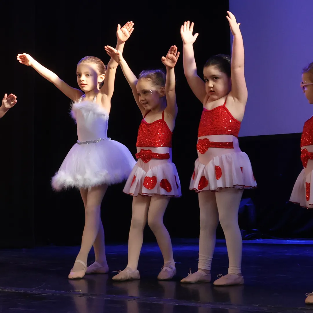 Young dancers in red and white costumes performing ballet on stage