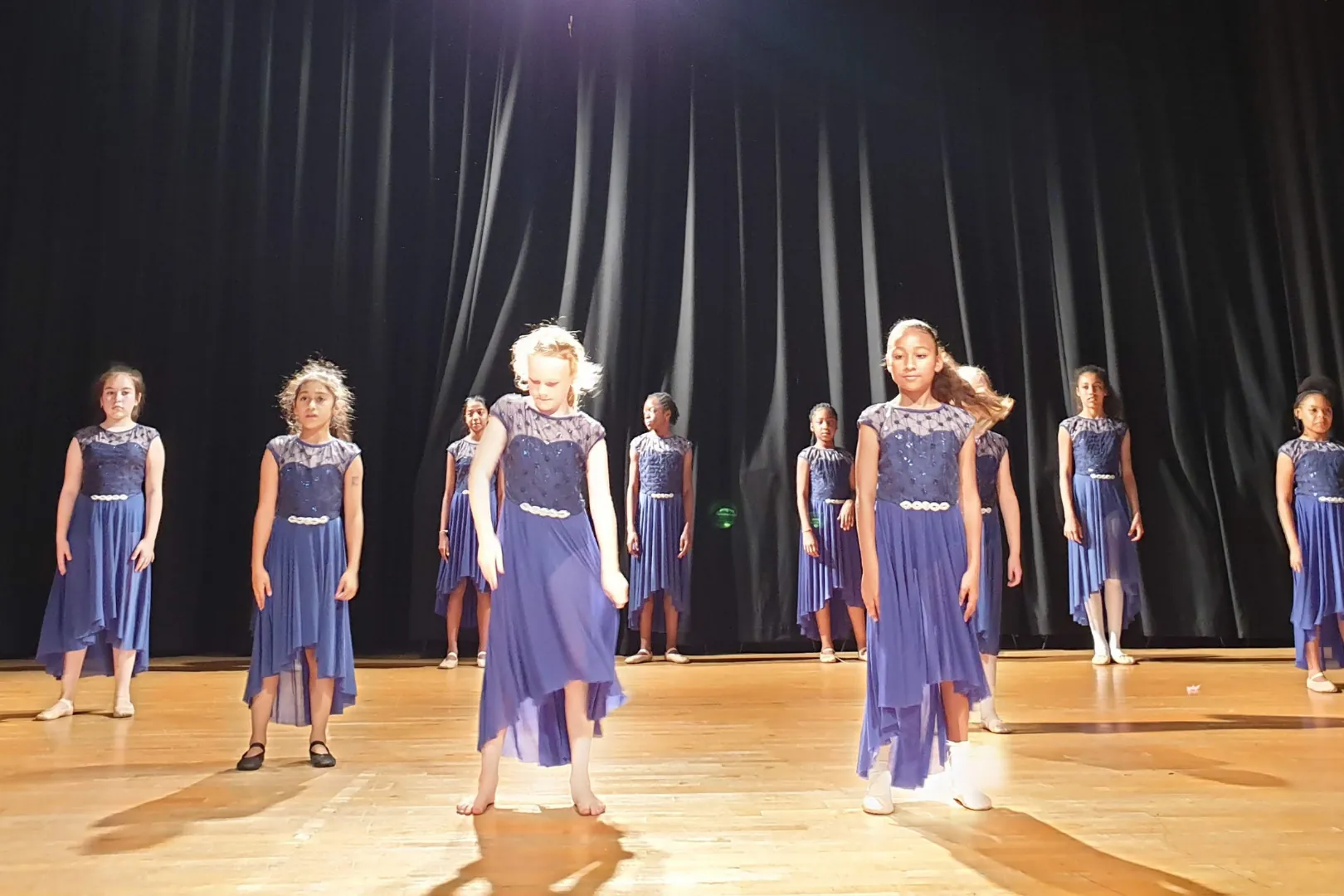 Modern dancers in blue dresses performing on stage