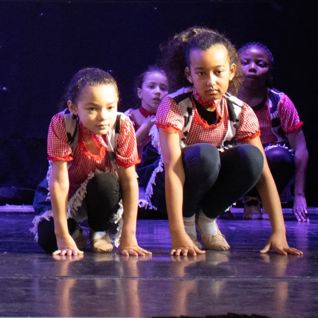 Young dancers crouching in a modern routine under purple light