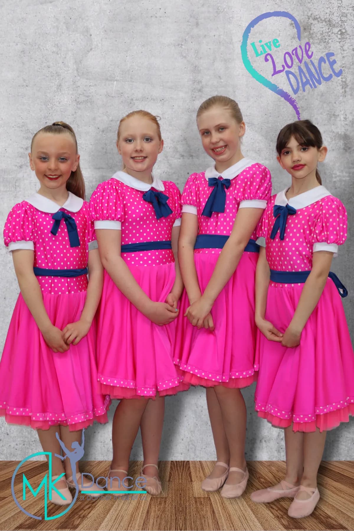 Four girls in bright pink dresses posing for a ballet performance photo