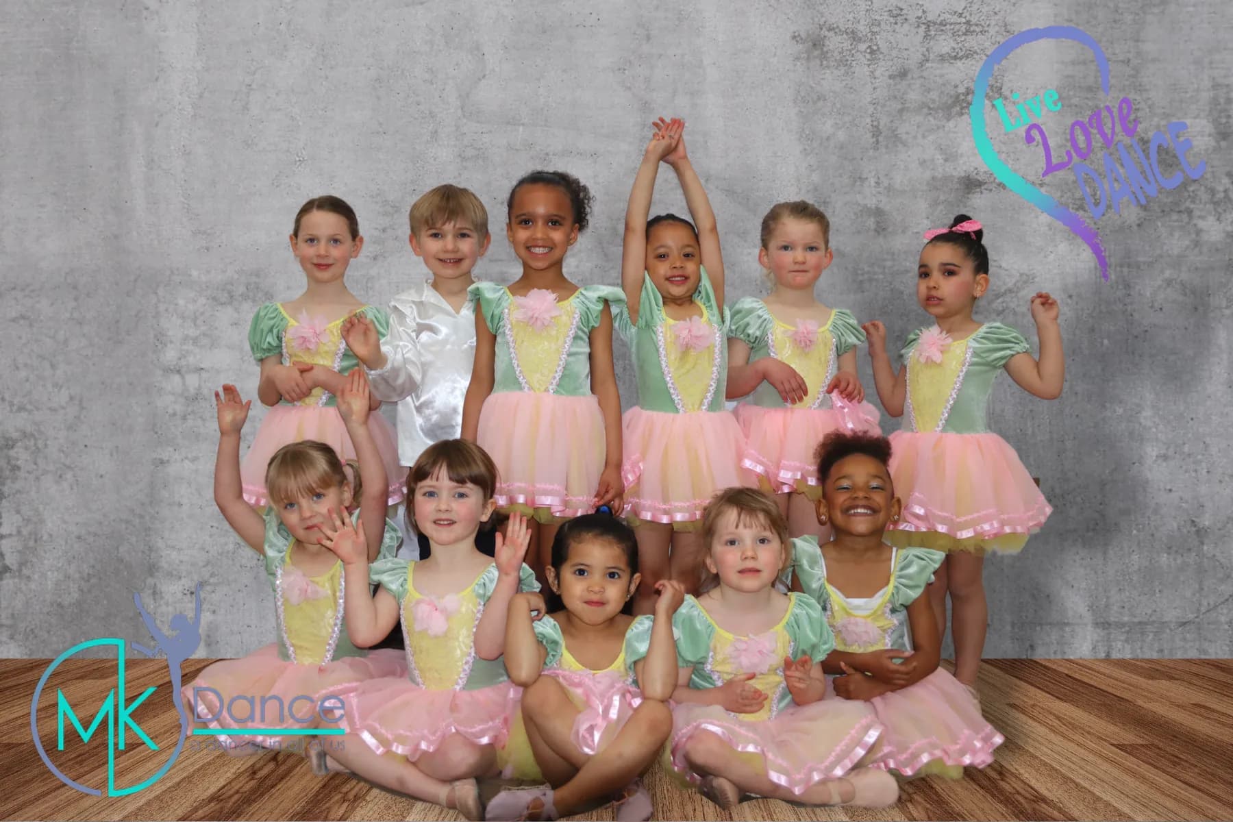 A group of young ballet dancers in pink tutus posing at a photo shoot
