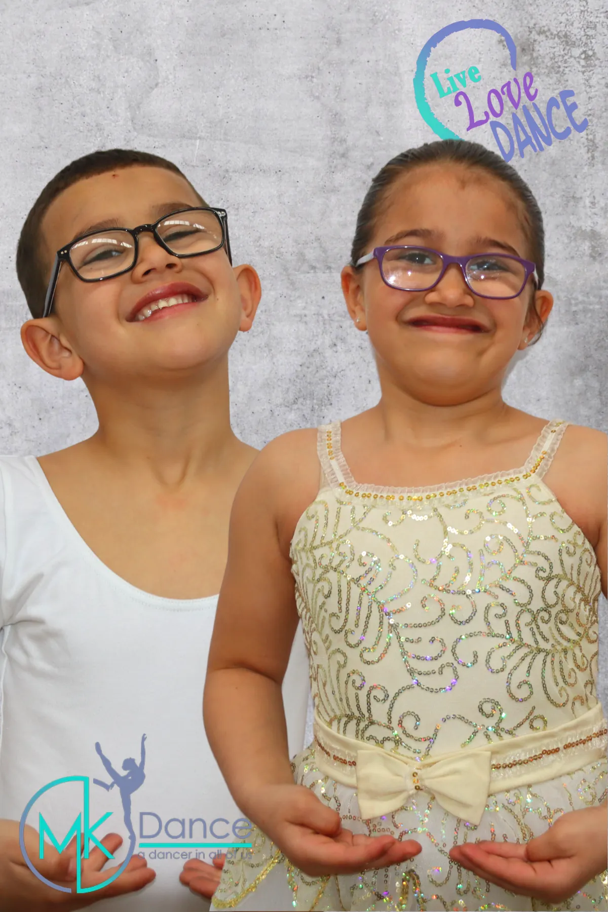 Two young siblings in dance costumes smiling at a photo shoot