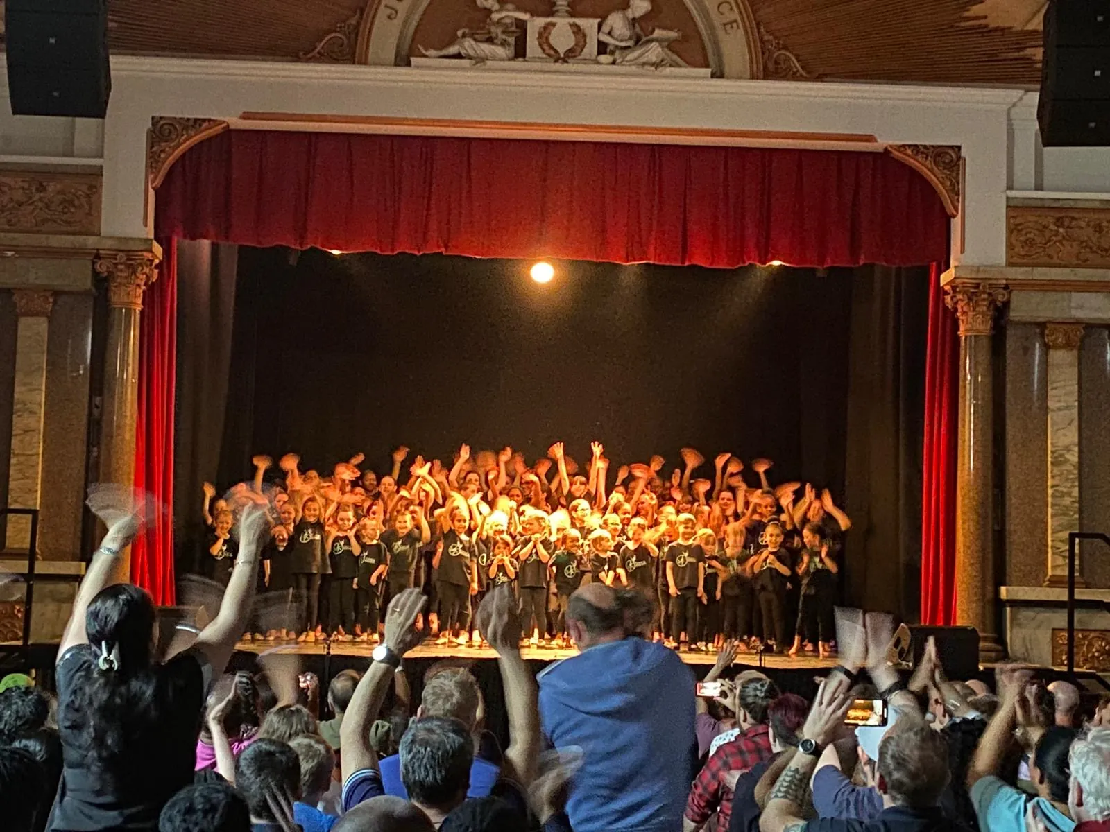 A full stage of dancers performing to an audience in a theatre hall
