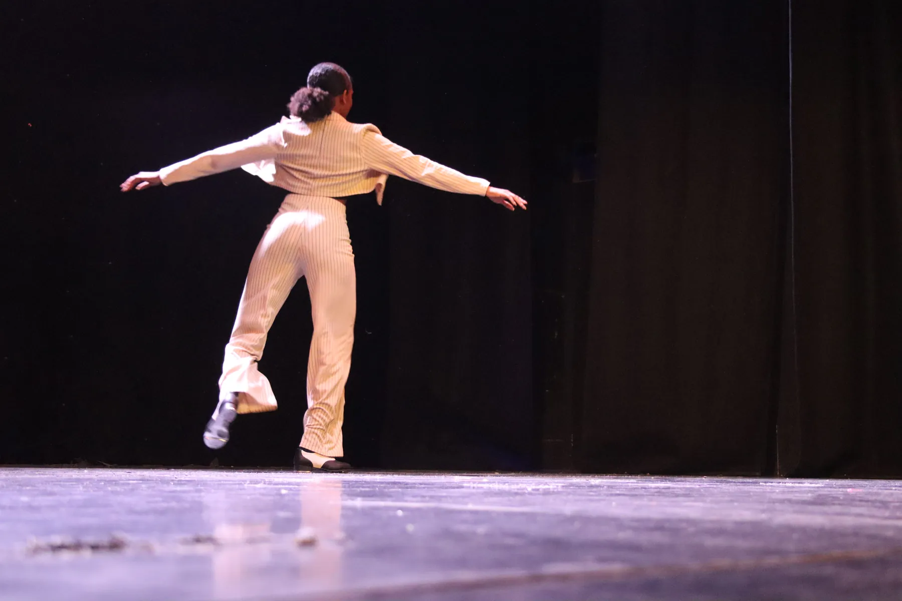 A solo dancer in cream performing on stage