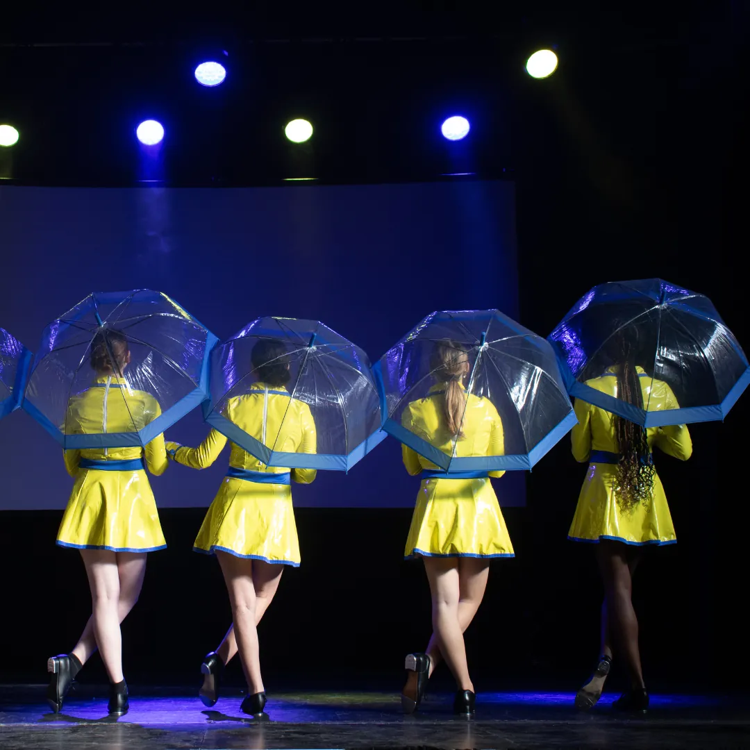 Dancers in yellow costumes performing with umbrellas on stage